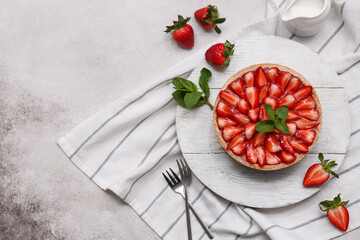 Wooden board of sweet strawberry tart with mint and jug of fresh milk on white background