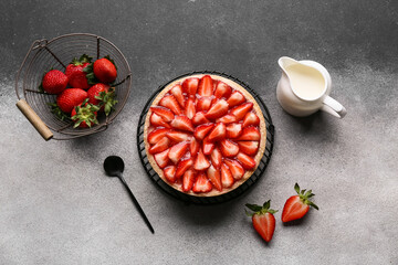 Stand with sweet strawberry tart and jug of fresh milk on grunge background