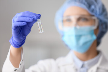 Female scientist with ampoule in laboratory, closeup