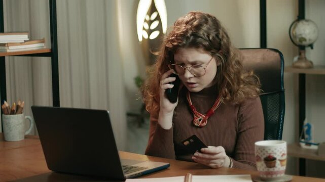 Worried woman calling customer service while holding a credit card, showing concern during a financial issue at home.