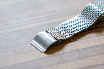 Close-up of a stainless steel tie on a wooden background.