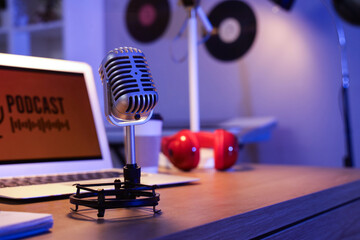 Professional microphone on podcaster's table in dark studio, closeup