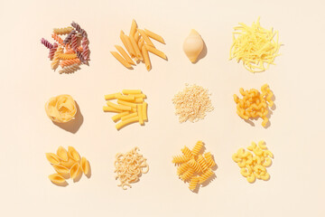 Composition with different types of raw tasty pasta on beige background