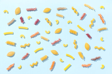 Composition with different types of raw tasty pasta on blue background