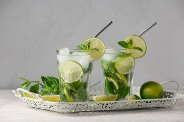 Tray with glasses of tasty mojito and ingredients on grey grunge background, closeup