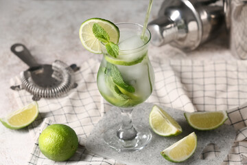 Composition with glass of tasty mojito, napkin and cutting board on grey grunge background, closeup