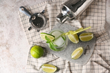 Composition with glass of tasty mojito, napkin and cutting board on white grunge background