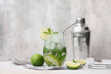 Glass of tasty mojito, napkin and lime on white background, closeup