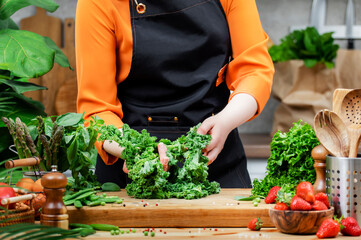 Woman chef engages in preparing a variety of fresh vegetables while promoting a healthy vegan lifestyle in a home kitchen