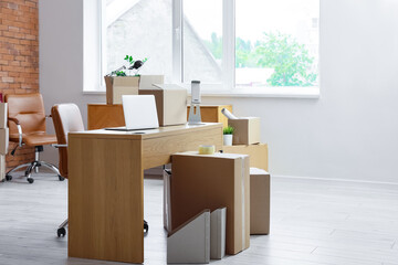 Workplace with laptop and cardboard boxes in office on moving day
