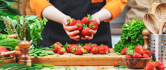 Cooking fresh strawberries and vegetables for a healthy vegan meal in a vibrant kitchen