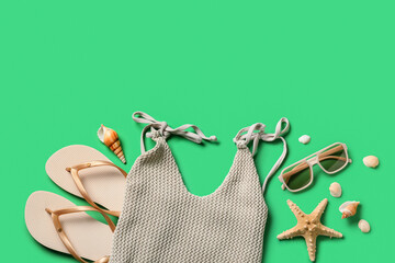 Summer composition with swimsuit, seashells and beach accessories on green background