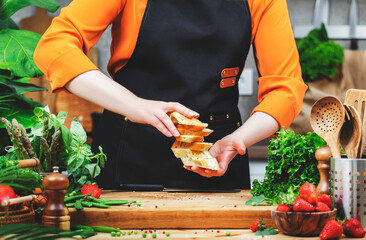 In a bright kitchen, a chef skillfully layers fresh bread while preparing a healthy meal, surrounded by a variety of ingredients.