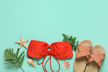 Composition with swimsuit, tropical leaves and flip-flops on turquoise background