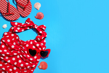 Composition with swimsuit, seashells and beach accessories on blue background, closeup
