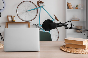 Podcaster's workplace with laptop, books and microphone in studio