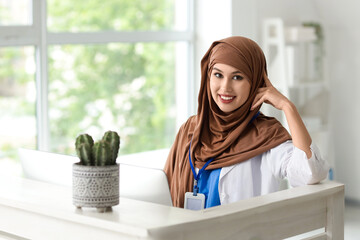 Female Muslim medical intern near reception in clinic