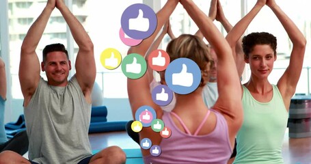 Instructor in fitness studio lifting arms, guiding group stretch as thumbs-up icons float overhead - Powered by Adobe