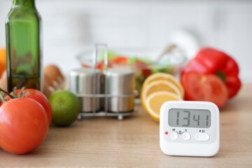 Modern kitchen timer and food on table in room, closeup