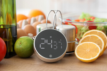 Modern kitchen timer with food, salt and pepper shakers on table in room, closeup