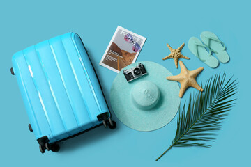 Composition with photo camera, suitcase and beach accessories on blue background