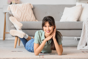 Smiling young woman lying on carpet at home