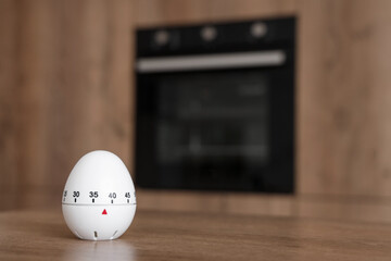 Kitchen timer on table against oven in room, closeup