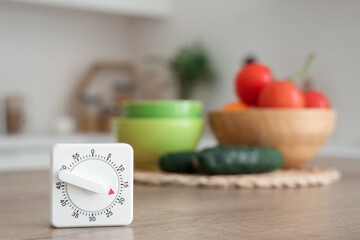 Kitchen timer and vegetables on table in room, closeup