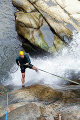 Latin american man rappelling down a waterfall, demonstrating skill and enjoying extreme sport in a...