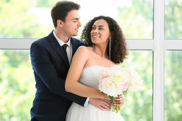 Young couple hugging near window on their wedding day