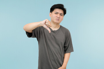 young asian man giving thumbs down showing disagree or dislike in studio background