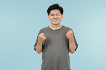 young asian man celebrating success in victory gesture in studio background