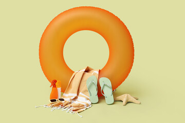 Inflatable ring, bottles of sunscreen cream and beach accessories on green background