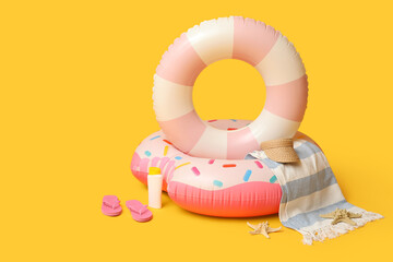 Inflatable rings and beach accessories on orange background, closeup