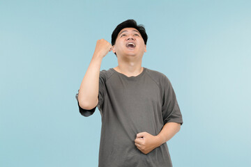 young asian man celebrating success in victory gesture in studio background