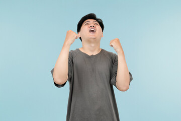 young asian man celebrating success in victory gesture in studio background