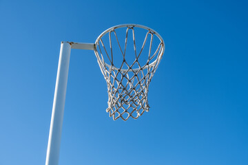 Close-up view of a netball hoop and net against a clear blue sky. Copy space for design. Concept of outdoor sport, active community infrastructure, and recreational facilities