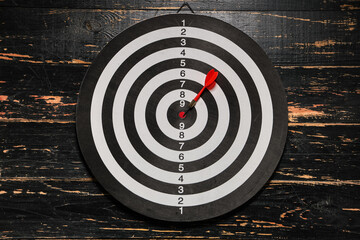 Board with dart on wooden  background