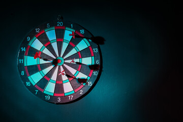 Board with darts hanging on dark wall