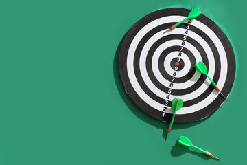 Board with darts on green background