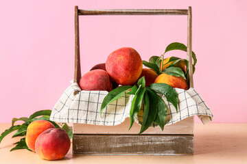 Basket of fresh peaches on pink background