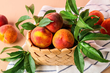 Wicker basket of fresh peaches on pink background