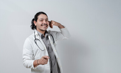 Smiling doctor pointing at you gesturing call. Doctor gesturing call