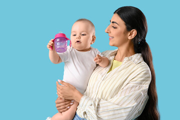 Mother with her baby and bottle of water on blue background