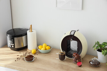 Modern coffee machine with capsules and beans on counter in kitchen