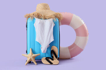 Inflatable ring, suitcase, swimsuit and beach accessories on lilac background, closeup