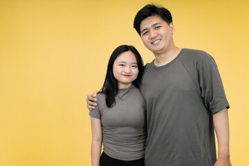 Fototapeta premium happy young asian couple smiling in yellow background studio