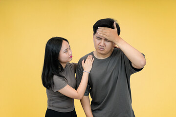 couple showing man in stressful moment while woman showing concern in studio yellow background