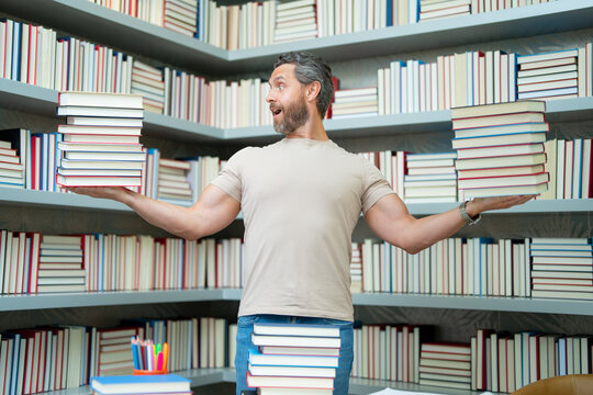 Portrait of teacher in library classroom. Teachers in university library. Teachers Day. Funny teacher hold many books. Crazy teacher with books. Excited teacher in school book library.