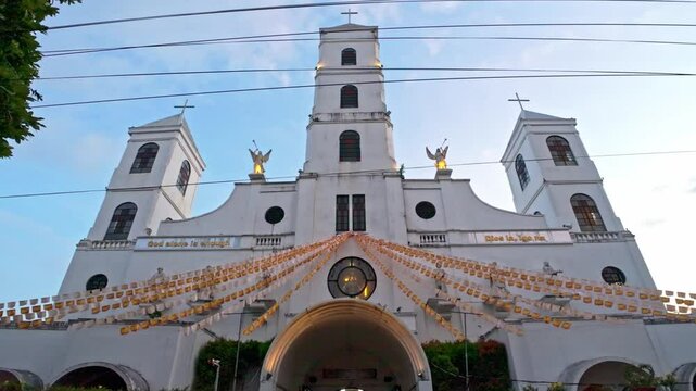 Front view of the white facade of Santo Ni&ntilde;o Parish Church in Tacloban with hanging decorations and bell towers.